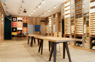 Photograph of solid antique heartpine shelving and tables, mirrors, and integrated lighting produced by Townsend Design for Warby Parker's NYC Meatpacking District retail store project.